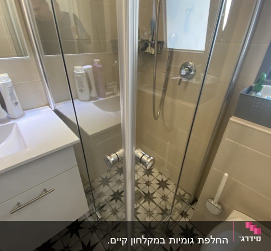 מקלחת עם דלתות זכוכית ורצפה מעוצבת